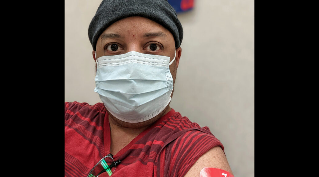 Selfie of Pax wearing a mask and a bandage on their upper left arm, just after getting a COVID booster shot.