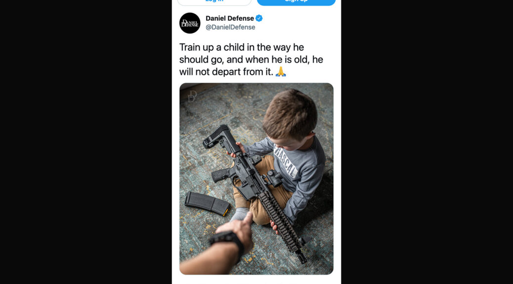 Screenshot from the Internet Archive of a tweet by Daniel Defense, showing a toddler sitting on the floor holding a rifle. The text reads “Train up a child in the way he should go, and when he is old, he will not depart from it”, with an emoji of hands together in prayer.